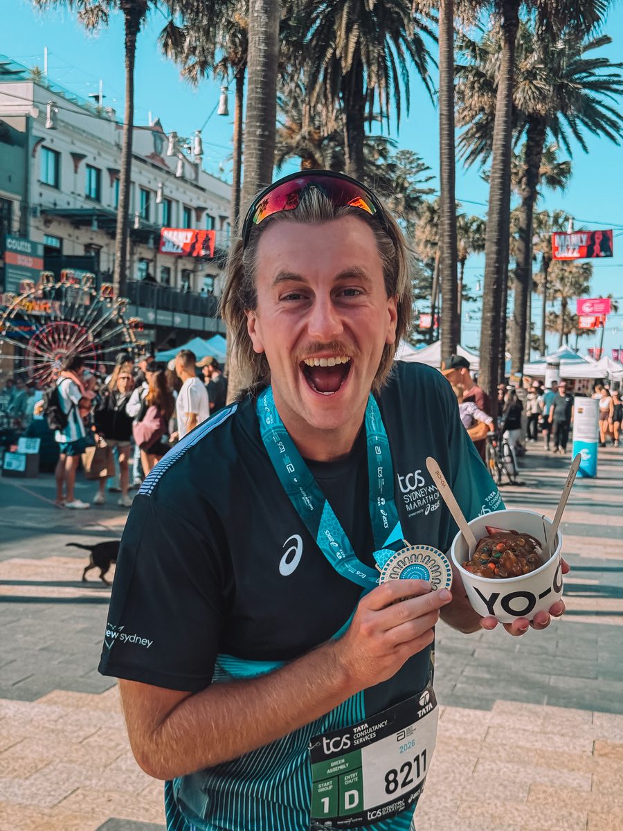Julien avec sa médaille et un açaï sur la promenade de Bondi Beach, après la course