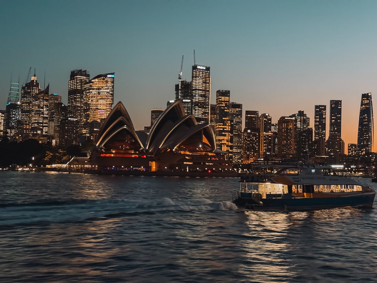 Un ferry devant l'Opéra de Sydney illuminé à la tombée de la nuit
