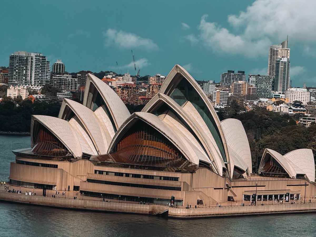 L'Opéra de Sydney et ses voiles blanches, devant les immeubles de la ville