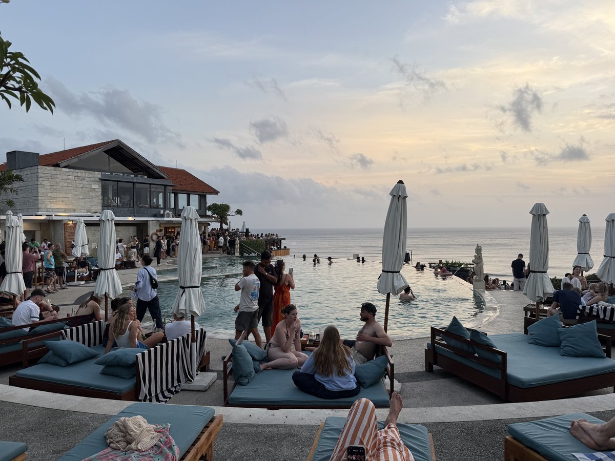 Un beach club et sa piscine à débordement en haut d'une falaise, face à l'océan en fin de journée