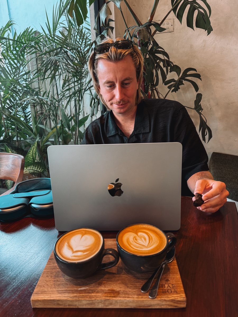 Julien devant son ordinateur portable dans un café de Canggu, deux cappuccinos posés sur la table