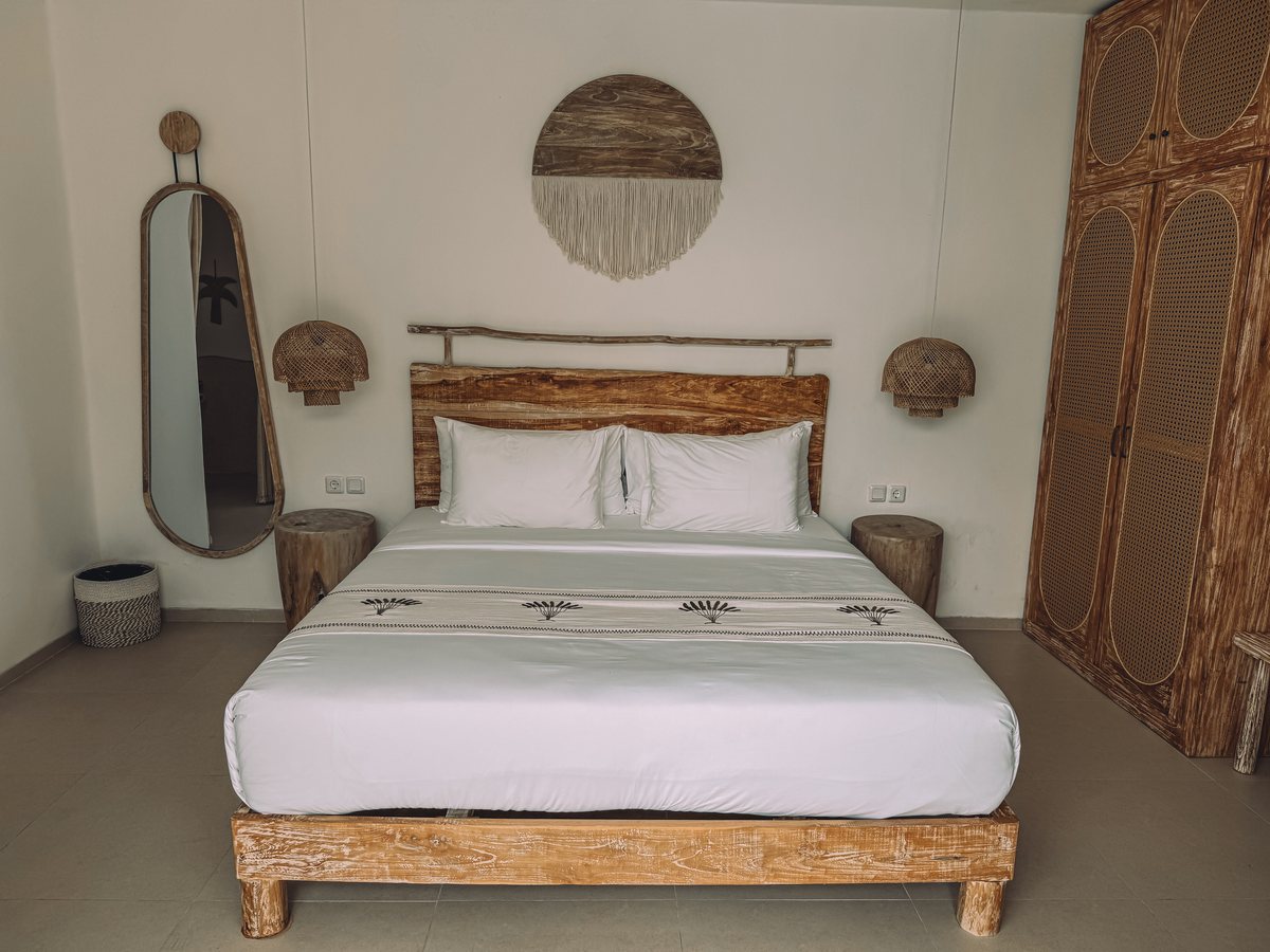 Une chambre claire avec un lit en bois brut et des appliques en osier