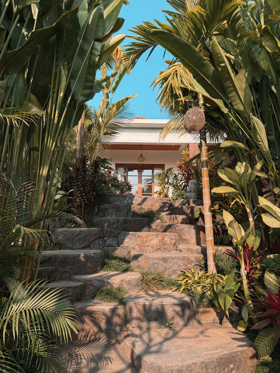 Escalier de pierre bordé de plantes tropicales menant à l'entrée d'une villa