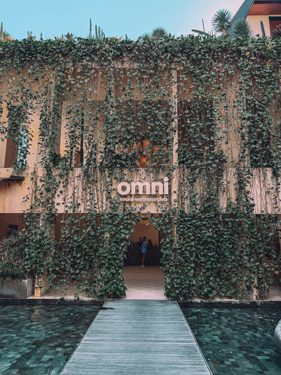 L'entrée du club Omni à Canggu, une façade couverte de lierre et une passerelle au dessus d'un bassin