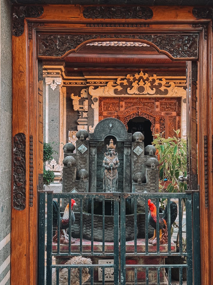 L'entrée sculptée d'un temple familial balinais, avec deux coqs devant la grille
