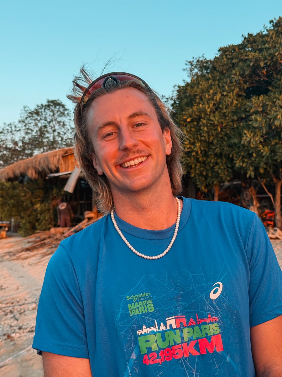 Julien sur une plage à la lumière du coucher de soleil, en t shirt du marathon de Paris