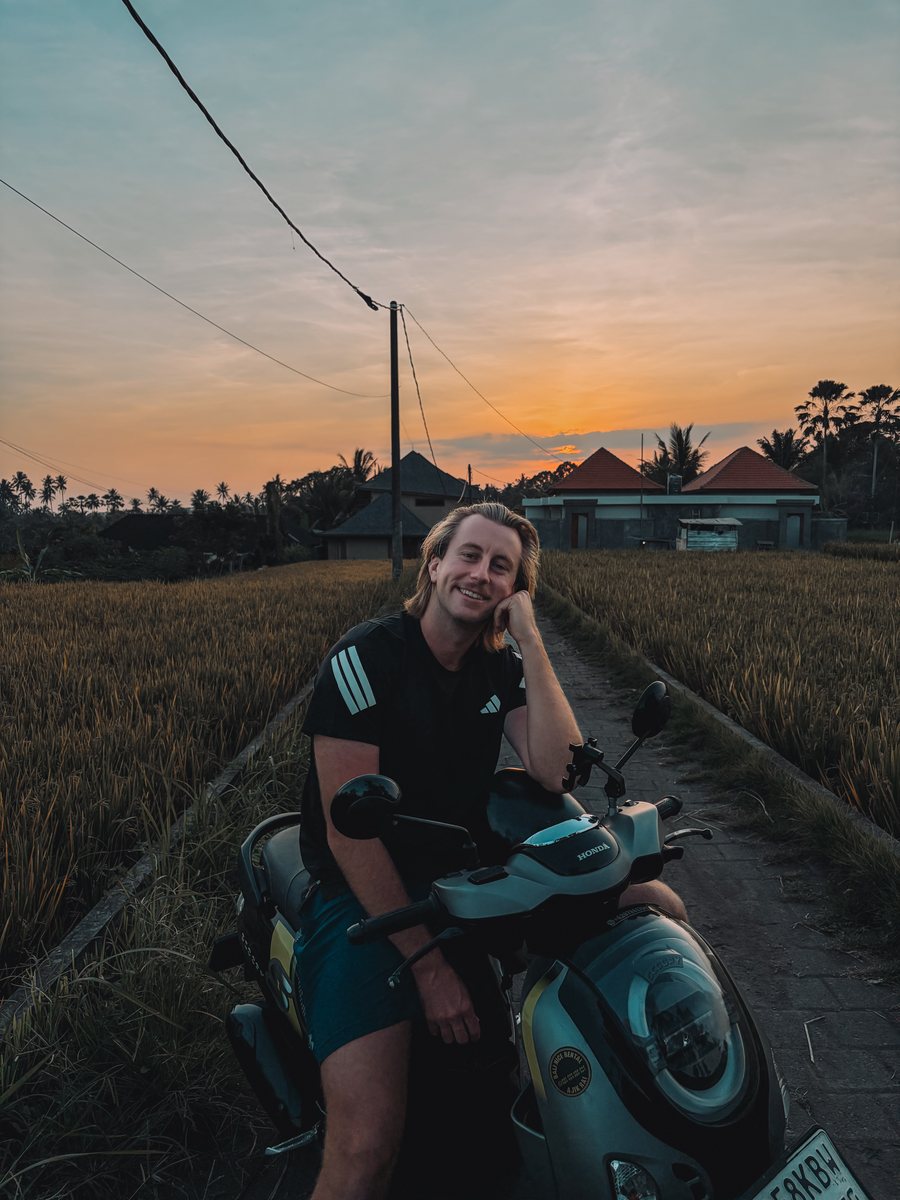 Julien sur un scooter au milieu des rizières, au coucher du soleil