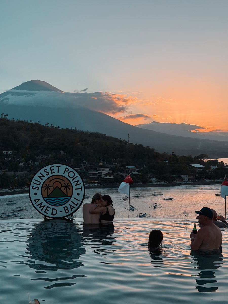 Une piscine à débordement face au volcan au coucher du soleil, avec un panneau Sunset Point Amed Bali