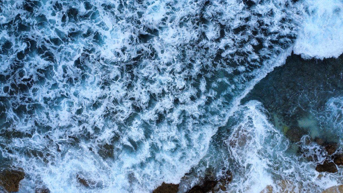 Vue aérienne à la verticale sur des vagues écumantes au dessus d'un récif