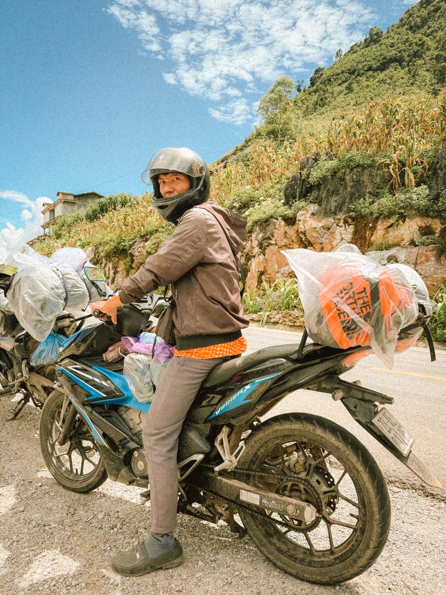 Une conductrice sur sa moto, les sacs emballés dans du plastique à l'arrière