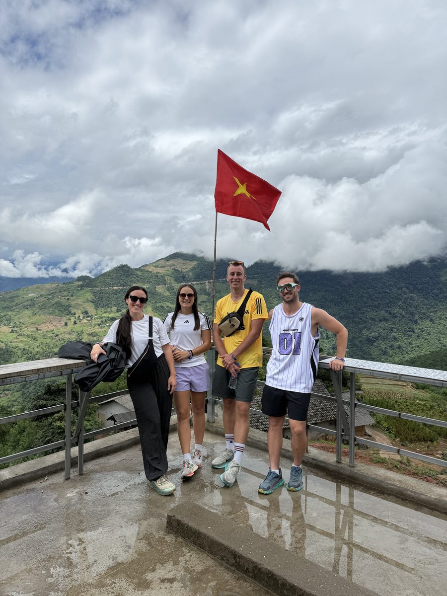 Quatre voyageurs devant le drapeau vietnamien, les montagnes dans les nuages