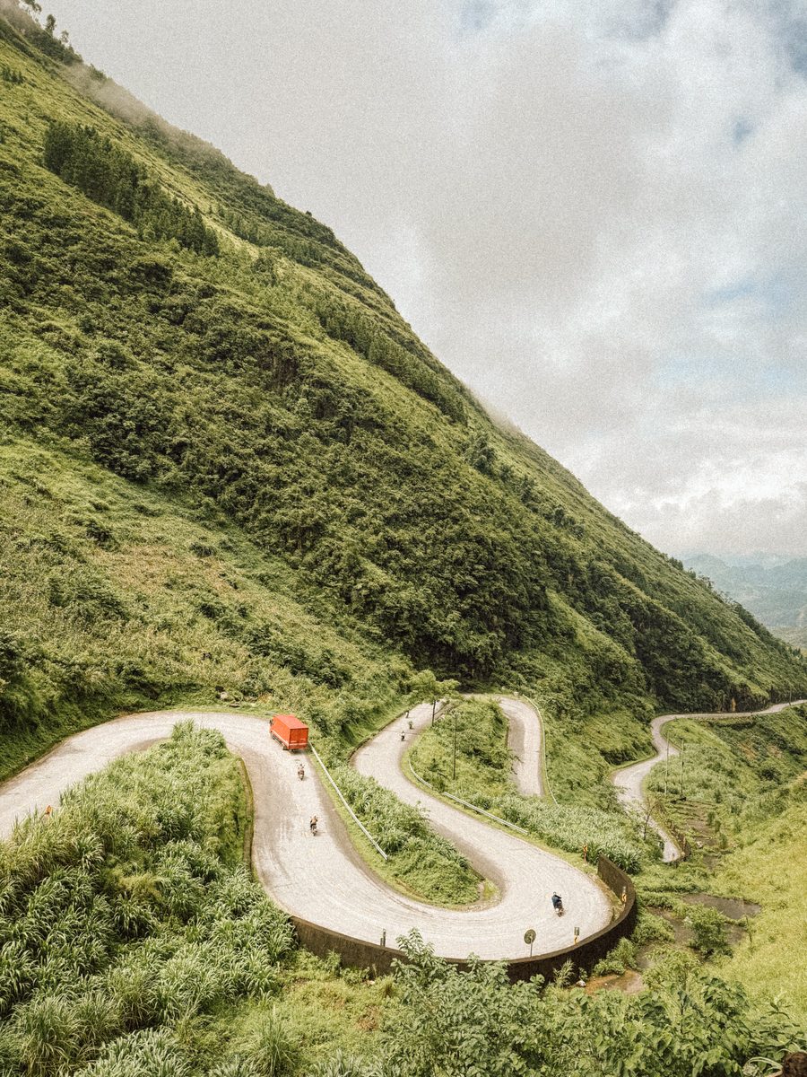 Les lacets de la route et un camion orange dans un virage en épingle