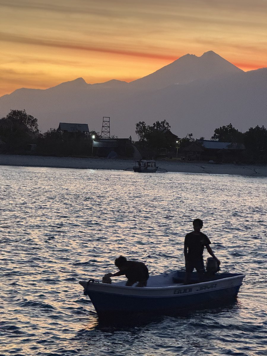 Deux pêcheurs dans leur barque au crépuscule, un volcan au loin
