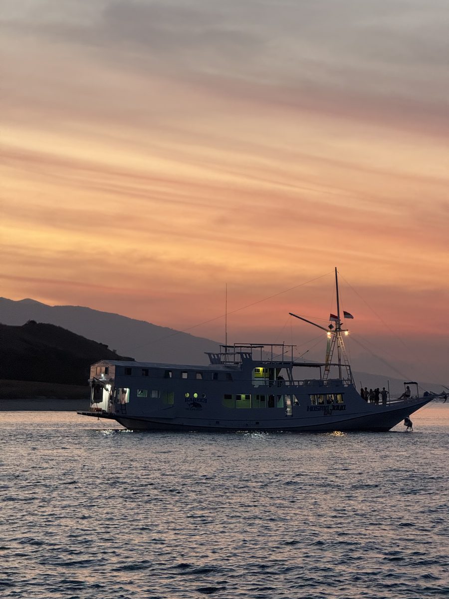 Le bateau de croisière au mouillage devant les collines, au coucher du soleil