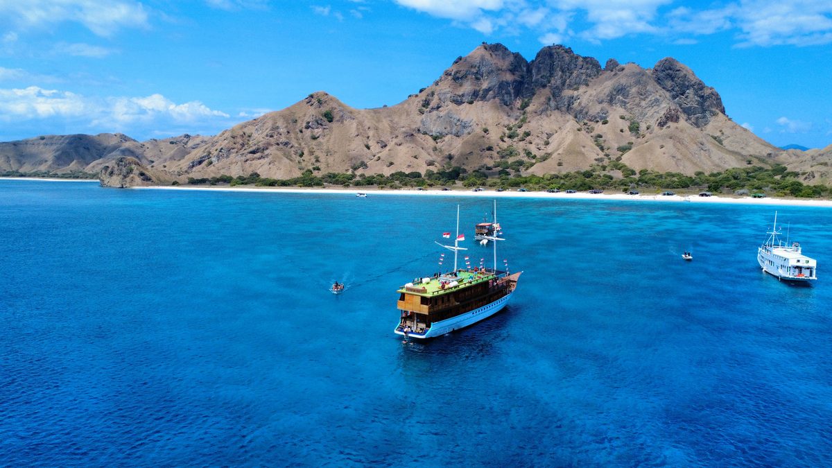 Le bateau au mouillage dans une eau bleu profond, devant les collines de Padar, vu du ciel