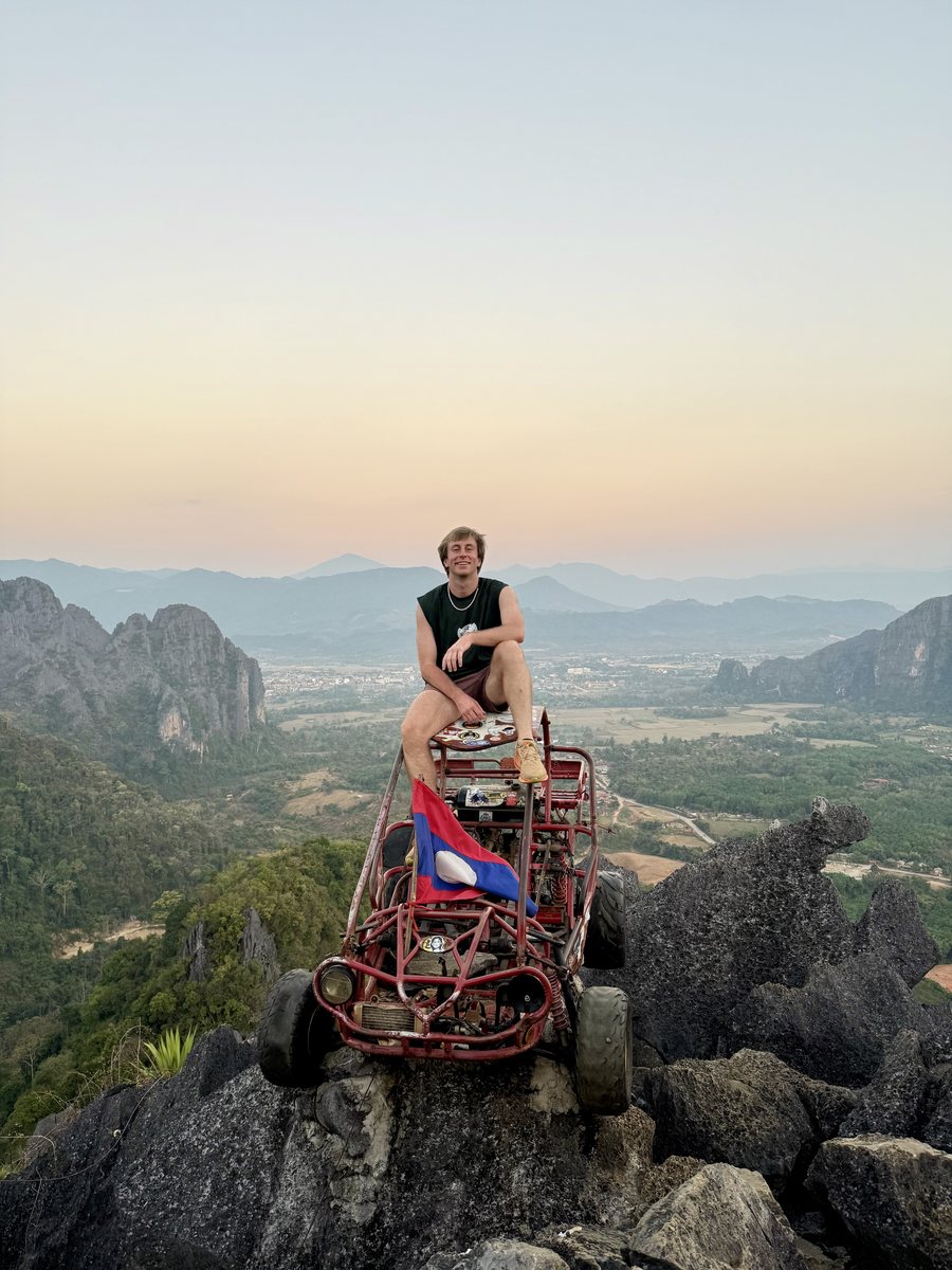 Julien assis sur un buggy garé au sommet d'un rocher, au coucher du soleil