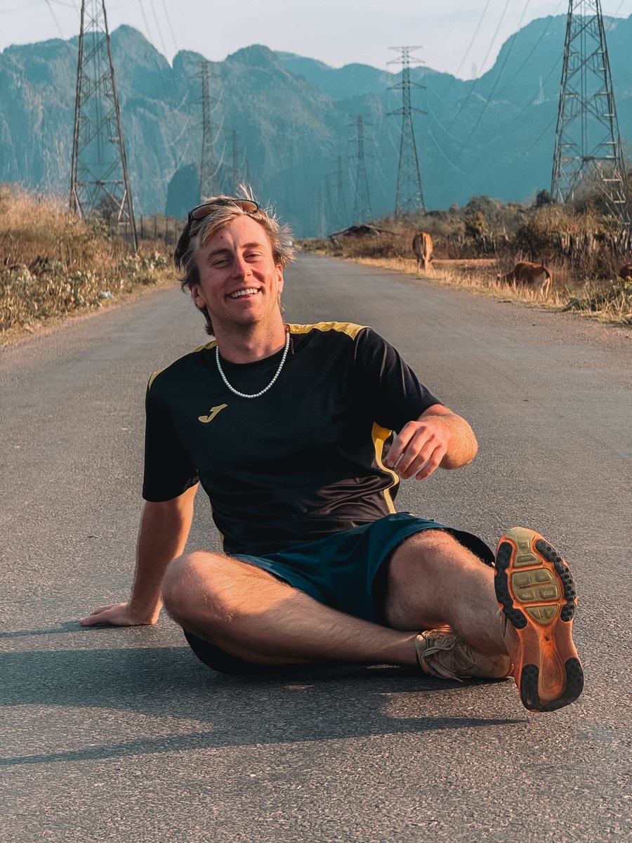 Julien assis en tenue de running au milieu d'une route, entre les montagnes