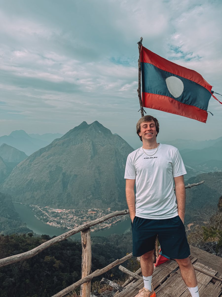 Julien devant un drapeau laotien, en haut d'un point de vue