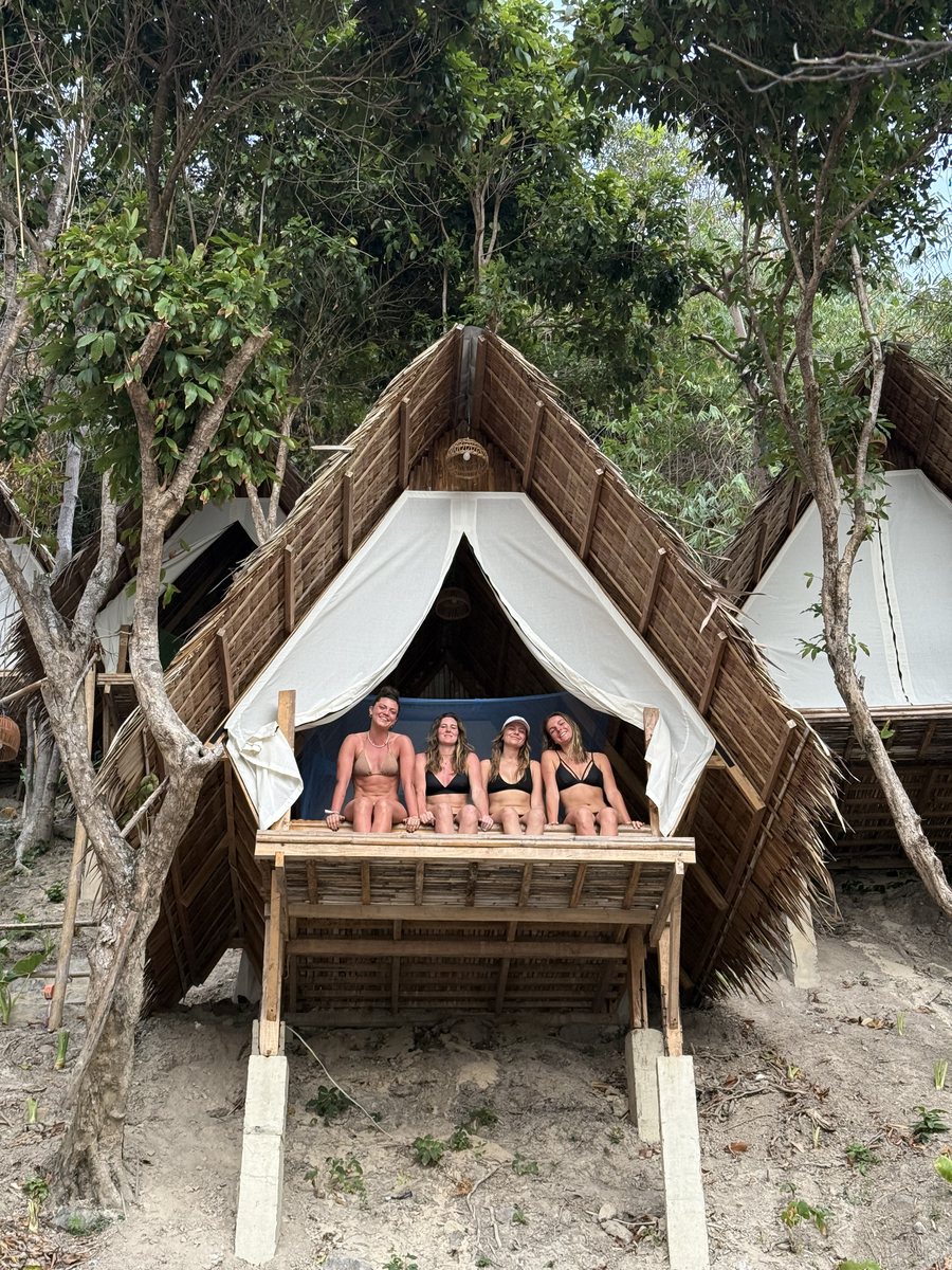 Groupe assis sur la terrasse d'une hutte de bivouac au toit de palme