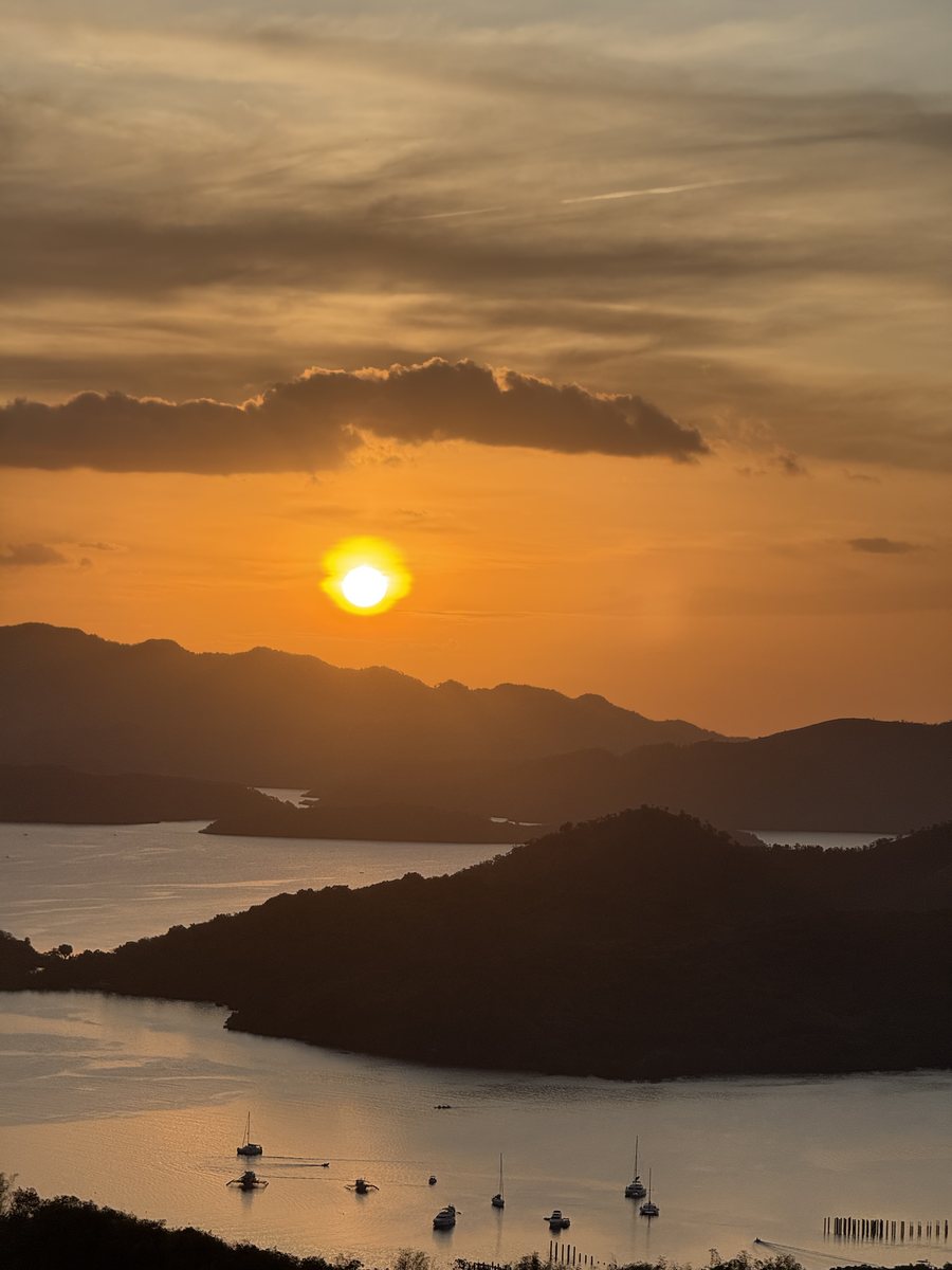 Coucher de soleil orange sur la baie de Coron et ses voiliers au mouillage