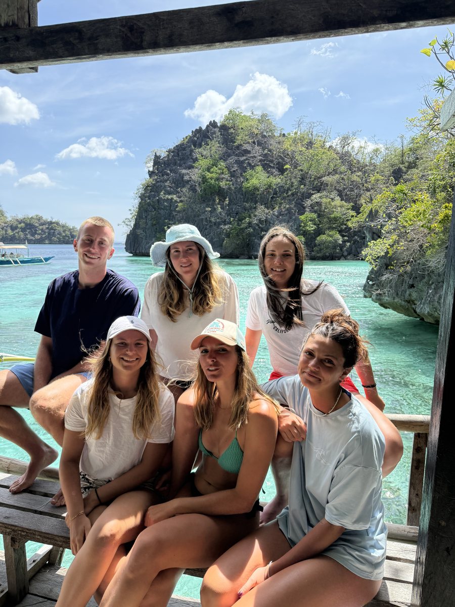 Groupe d'amis à l'avant d'un bateau, devant un piton calcaire et une eau claire