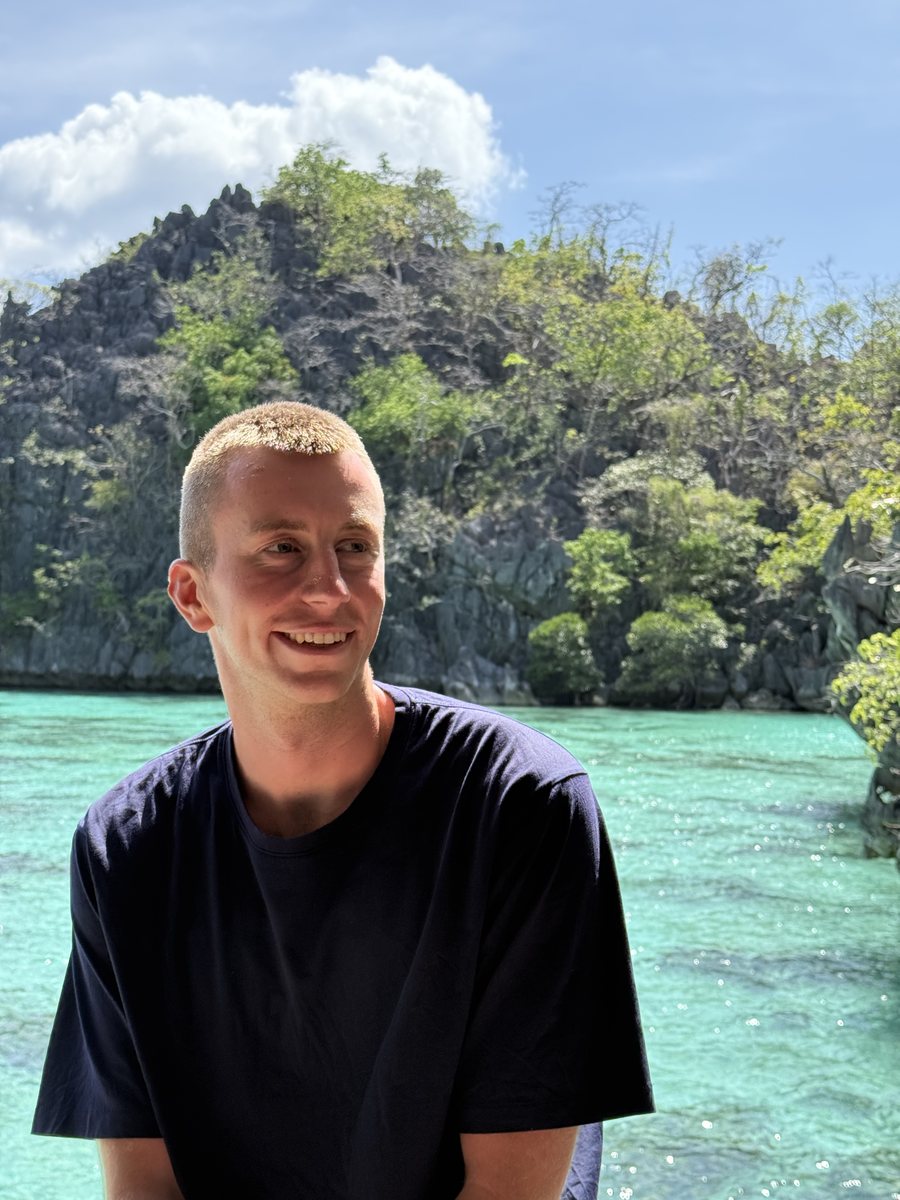 Portrait sur un bateau, devant une eau turquoise et des falaises calcaires
