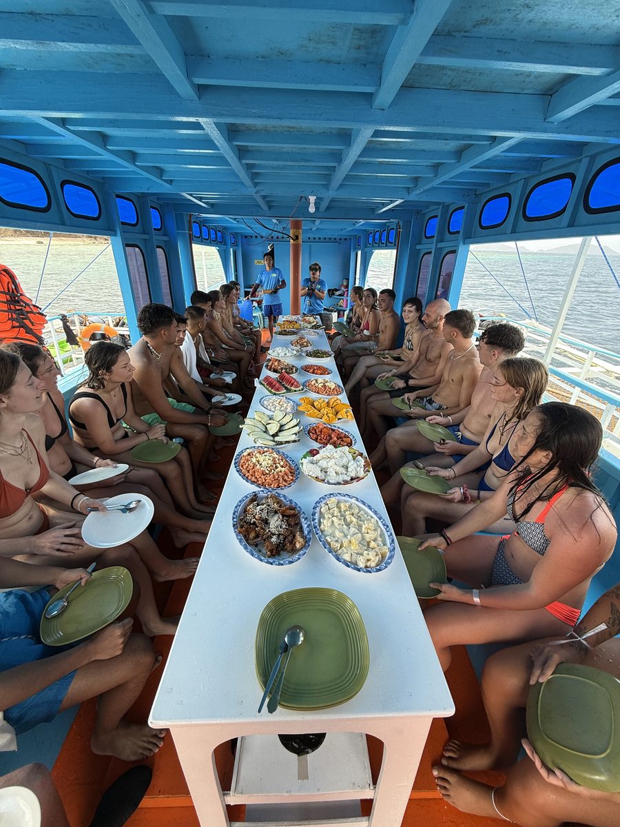 Voyageurs assis de part et d'autre d'une table dressée au milieu du pont
