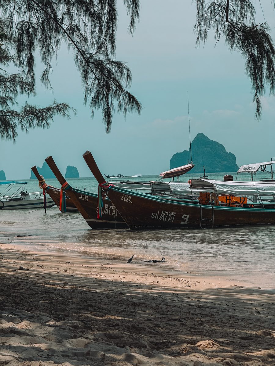 Bateaux à longue queue échoués sur une plage, îles karstiques au large