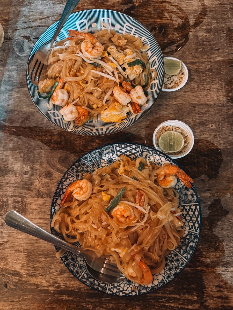 Deux assiettes de pad thaï aux crevettes sur une table en bois