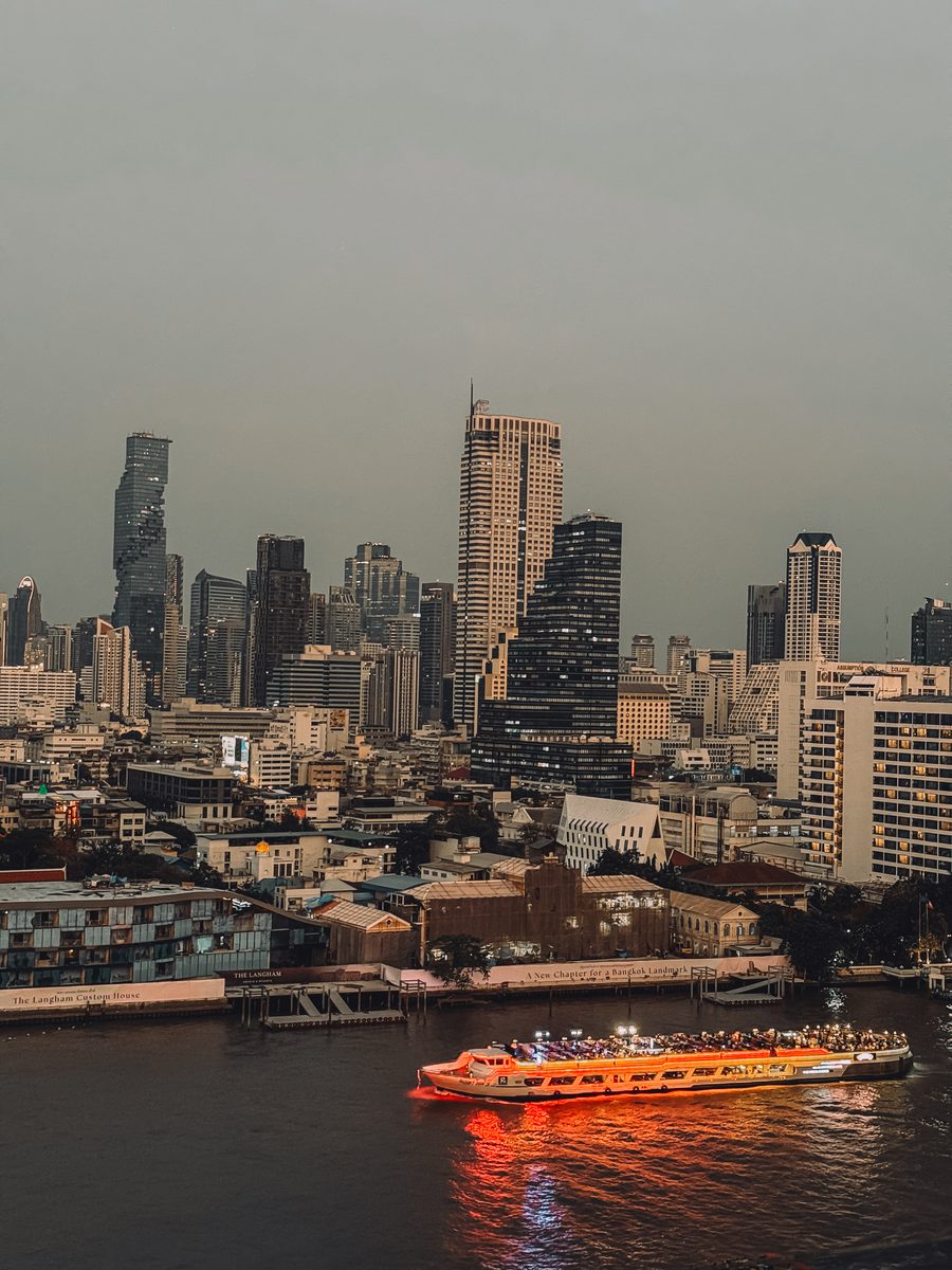 Bateau de la rivière Chao Phraya devant les tours de Bangkok à la tombée du jour
