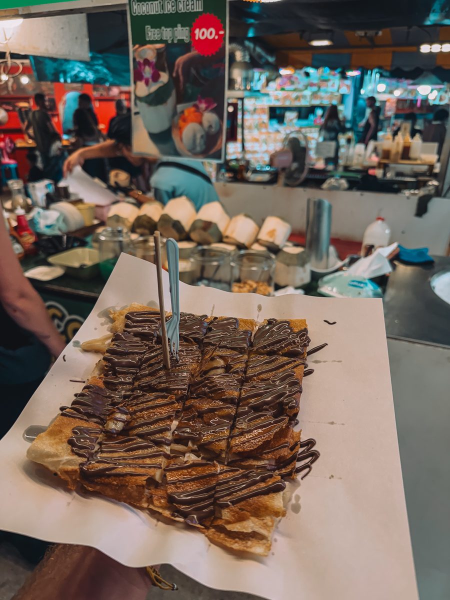 Roti à la banane et au chocolat découpé, sur un stand de marché de nuit