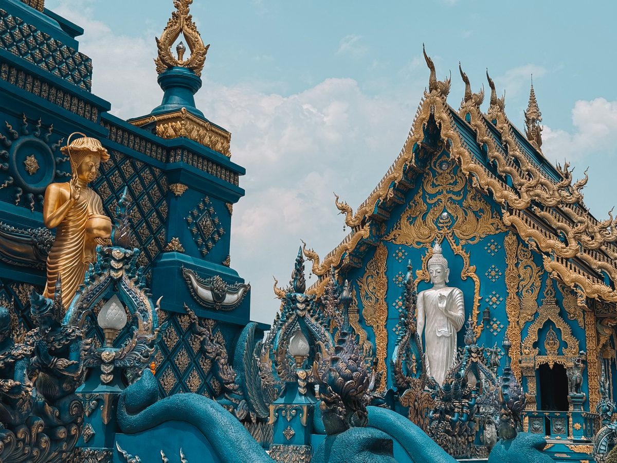 La façade bleu et or du Temple Bleu de Chiang Rai, nagas sculptés au premier plan
