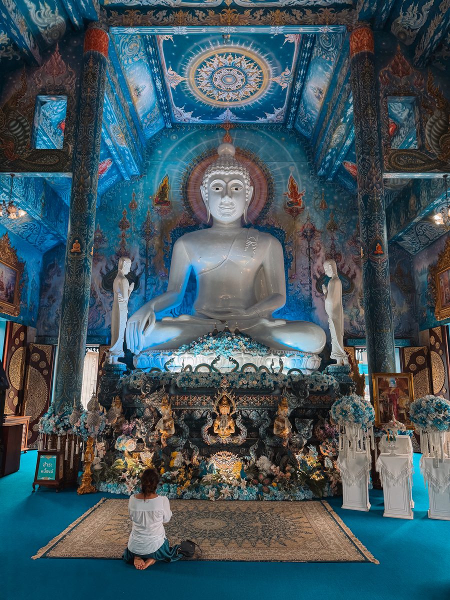 L'intérieur du Temple Bleu de Chiang Rai, grand bouddha blanc sur fond de fresques bleues