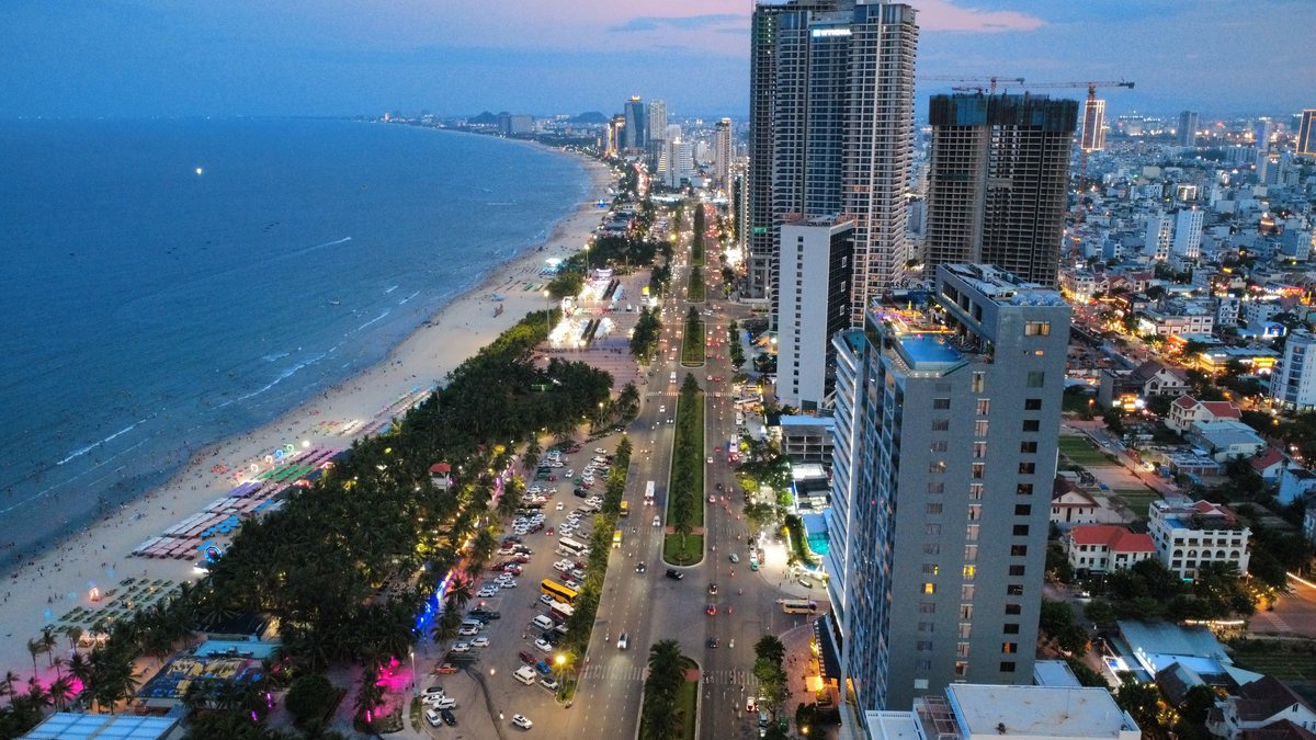 Front de mer de Da Nang à la tombée de la nuit, longue plage et tours éclairées, vue du ciel