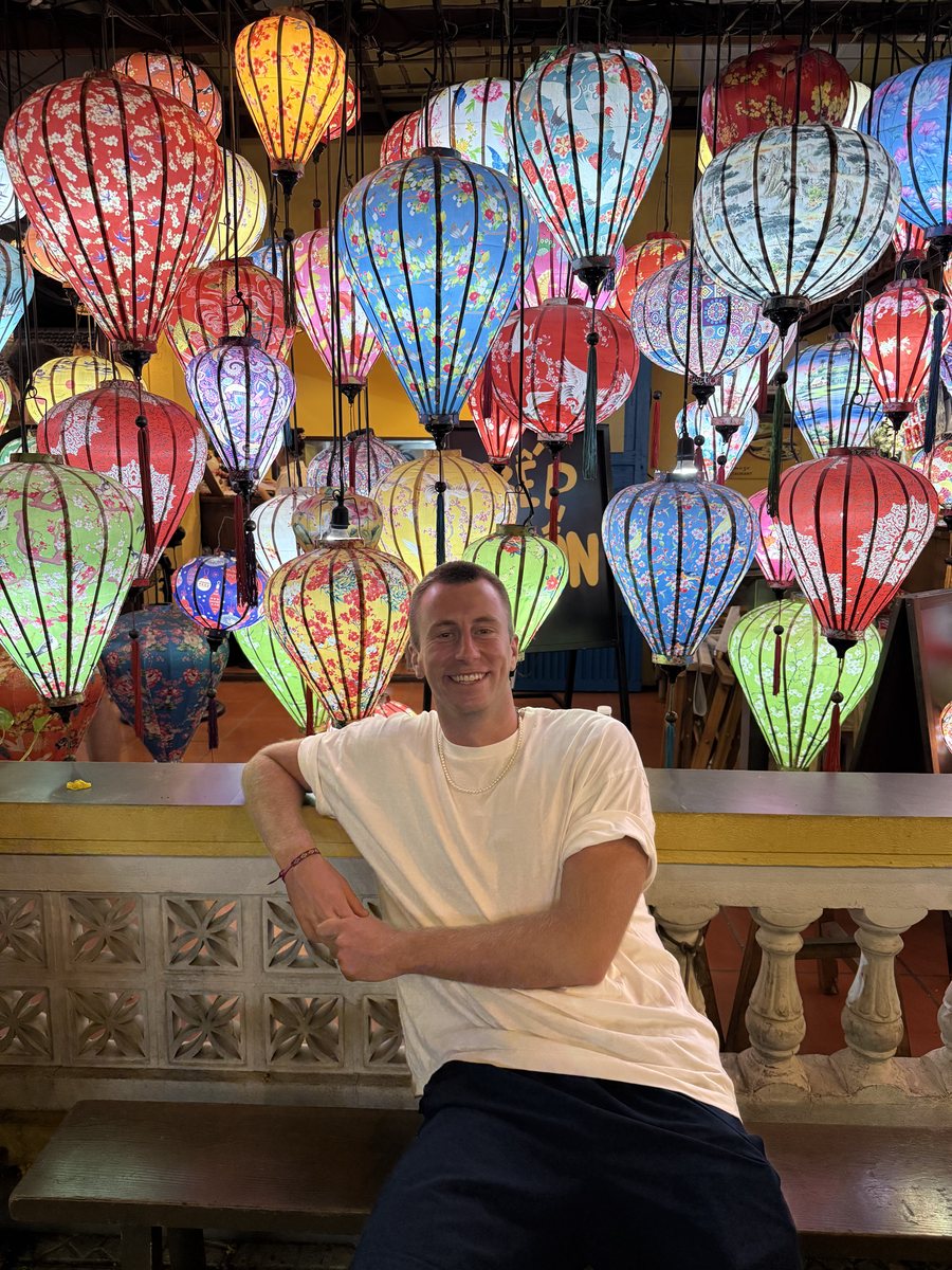 Julien devant un mur de lanternes en soie colorées, à Hoi An