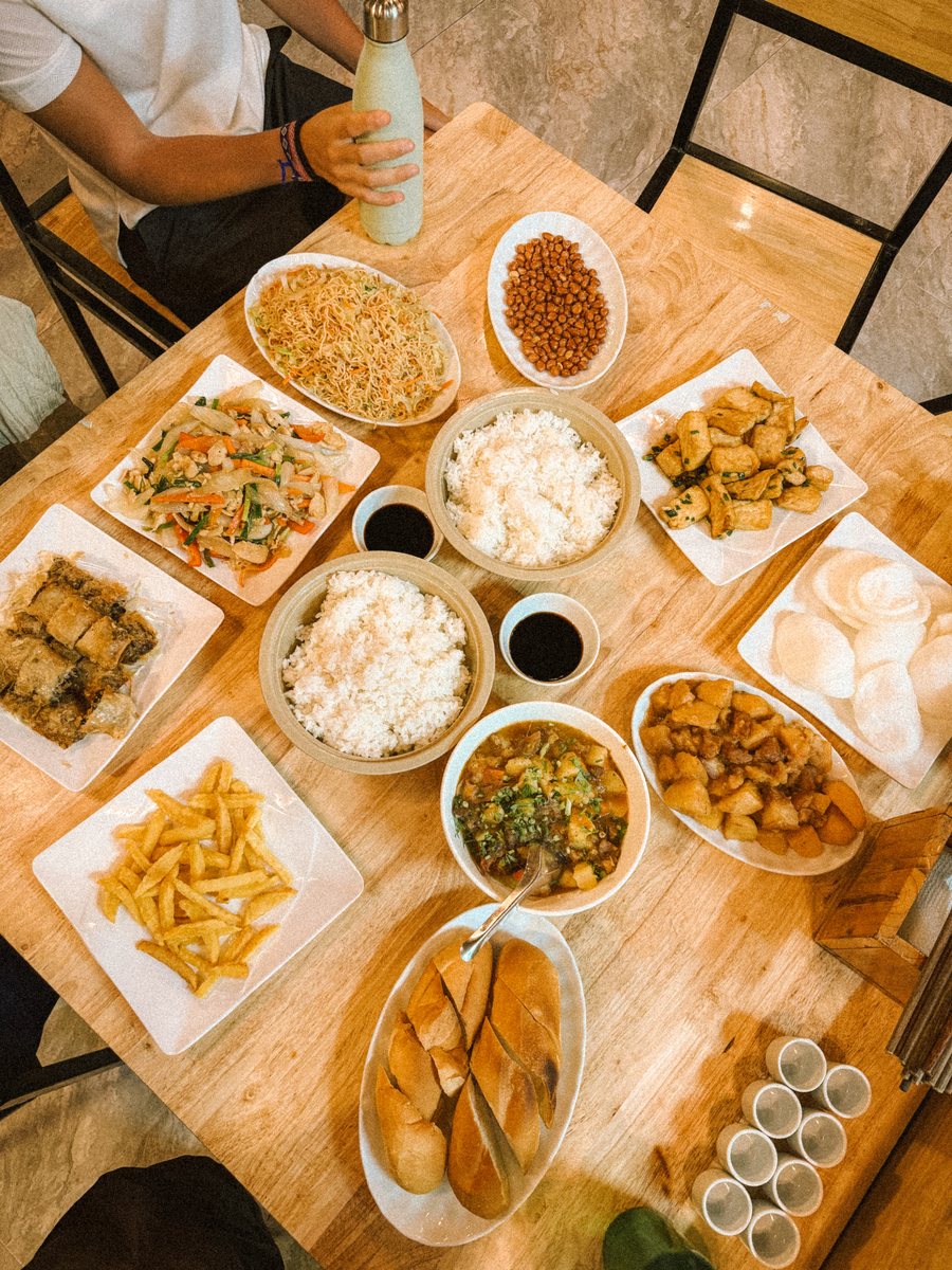 Table couverte de plats vietnamiens partagés, riz, nems et légumes sautés