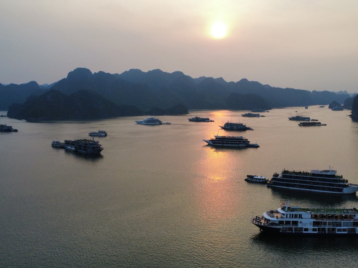 Bateaux de croisière à l'ancre entre les pitons calcaires de la baie, au coucher du soleil