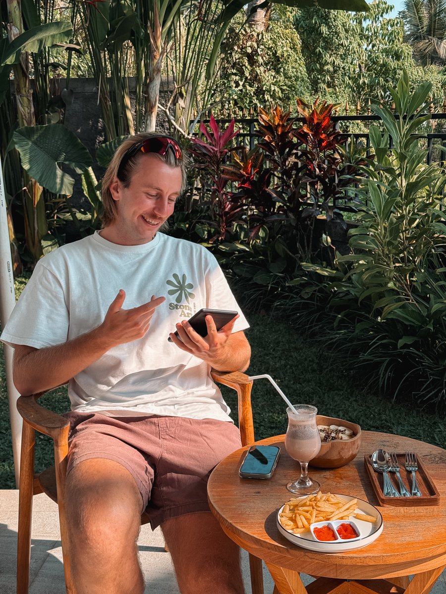 Julien consulte son téléphone à la table d'un jardin d'hôtel, à Ubud