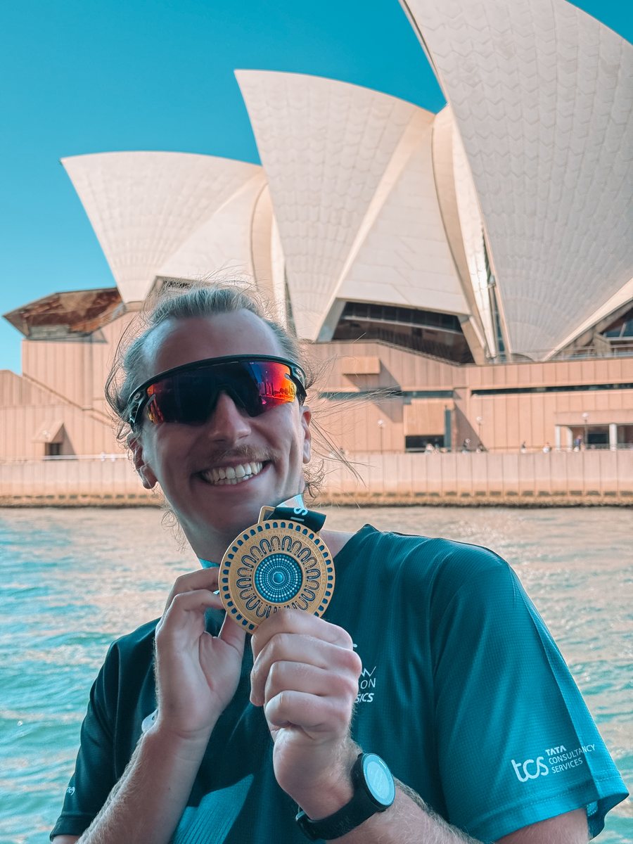 Julien montre sa médaille du marathon de Sydney devant l'Opéra
